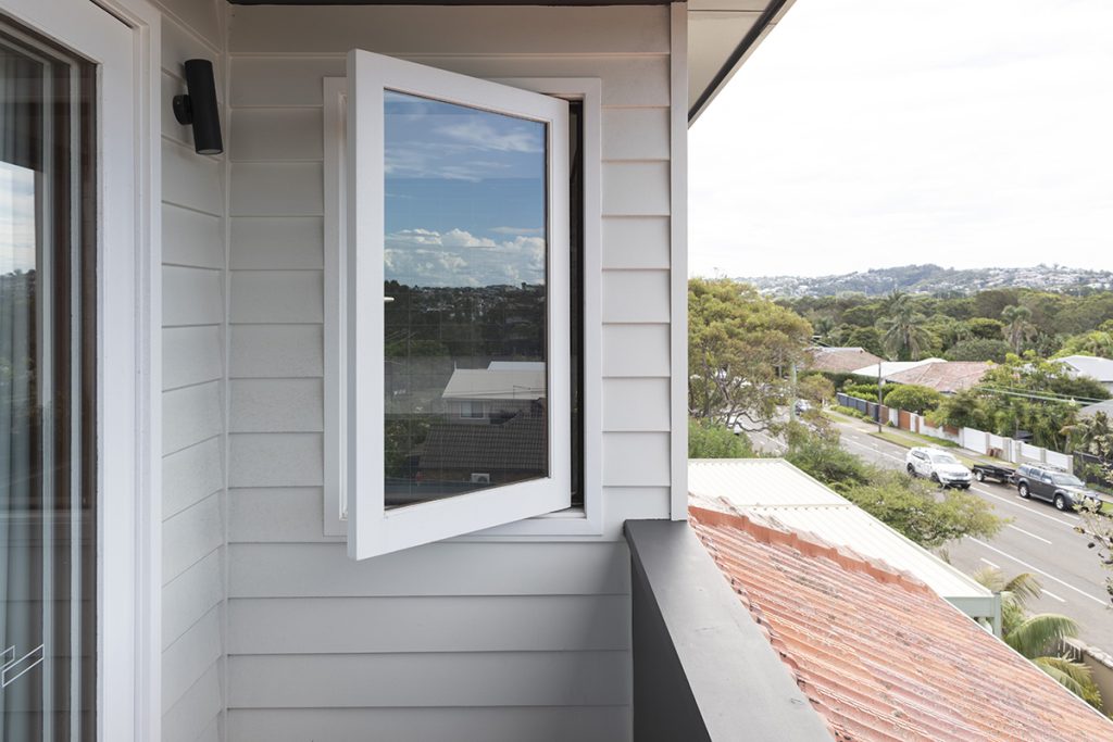 A casement window in a white painted finish on the upper floor of Re-Grow/Re-Wild House by Bastian Architecture